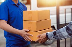 Asian delivery express courier young man use giving boxes to woman customer he wearing protective face mask at front home photo