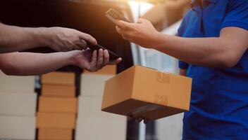 Asian delivery express courier young man use giving boxes to woman customer he wearing protective face mask at front home photo