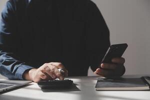 businessman working on desk office with using a calculator to calculate the numbers, finance accounting concept photo