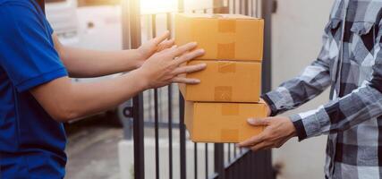 Asian delivery express courier young man use giving boxes to woman customer he wearing protective face mask at front home photo