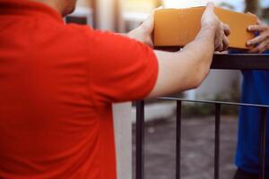 Asian delivery express courier young man use giving boxes to woman customer he wearing protective face mask at front home photo