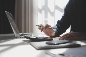 businessman working on desk office with using a calculator to calculate the numbers, finance accounting concept photo