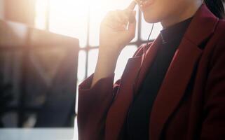 Friendly female helpline operator in call center. Young woman working in call center and holding microphone on headset with hand. photo