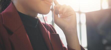 Friendly female helpline operator in call center. Young woman working in call center and holding microphone on headset with hand. photo