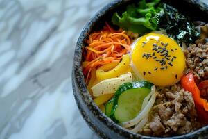 Bibimbap with rice, fried egg and vegetables in bowl photo