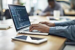 Close-up of hands typing on a laptop with code on the screen in an office photo
