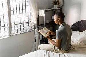 Man in gray shirt reading a book at home. photo
