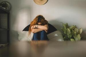 Front view of a sad woman sitting on the bed. photo