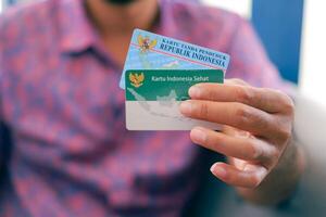 Man hand holding Kartu Tanda Penduduk, or ID card, or KTP in Indonesia, and a BPJS card, or the national health care slcard photo