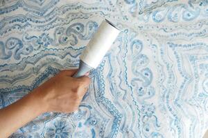 using an adhesive roller to remove lint and fluff from a bed . photo