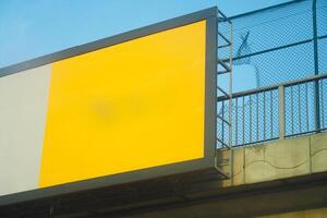 An empty yellow billboard is seen on a highway overpass against a blue sky backdrop photo