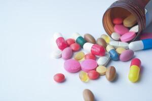 color pills spilling from container on isolated on white photo