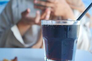 A person using a smartphone in the background while enjoying a refreshing cold drink photo