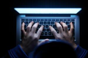 Closeup of Hands Typing on Laptop Keyboard in a Dark Workspace with a Glowing Effect photo