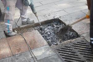 A group of workers using a jackhammer to break and remove concrete sections on a construction site photo