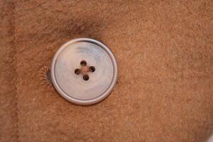 Closeup of a brown button on wool fabric, capturing intricate details and textile texture photo