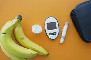 top view of diabetic measurement tools and banana on orange background photo