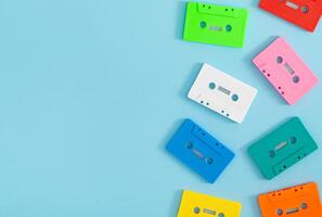 Colorful pattern made of retro audio cassette tapes on blue background with copy space. Creative concept of retro technology. 80's aesthetic retro style. Vintage cassette tape pattern idea. Flat lay. photo