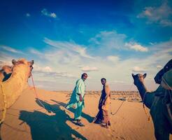 Two cameleers camel drivers with camels in dunes of Thar deser photo