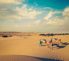 Two cameleers camel drivers with camels in dunes of Thar deser photo