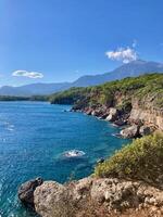 View of the cliffs and seishore with mountains and blue sky on the background photo