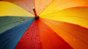 Close-up of a multicolored umbrella with water droplets, showcasing vibrant colors and a rainy day atmosphere. photo