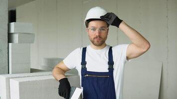 Portrait of a positive builder in a protective helmet on the construction site of the office video