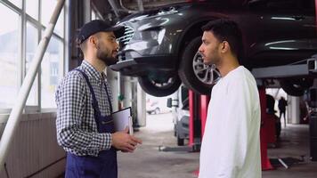 Smiling auto mechanic and indian client shaking hands in service video
