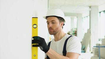 A man builder measures of the vertical deviation of plasterboard wall. Bubble level ruler close up view, measuring and leveling concept video