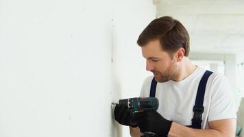 A man drywall worker or plasterer using cordless electric screwdriver to fix the plasterboard sheets to the metal profiles to build the new wall video