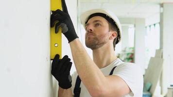 A man builder measures of the vertical deviation of plasterboard wall. Bubble level ruler close up view, measuring and leveling concept video