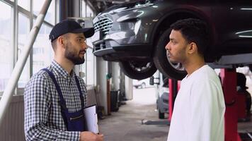 Smiling auto mechanic and indian client shaking hands in service video