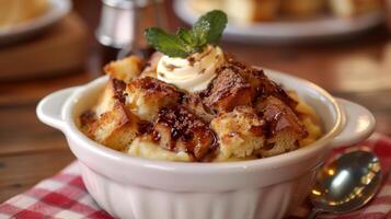 A bowl of delicious bread pudding dessert topped with whipped cream, mint, and drizzled with chocolate syrup. photo
