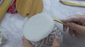 Person forms edges of clay circle with wooden spatula in shape of flower pot. Handmade and craft. Wooden tools on a marble table. Modeling clay for ceramic dishes. video