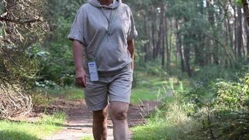 woman in the forest in beige sweatshirt takes her daily steps,breathes the air of pine forest,uses an application on her smartphone to record calories burned and count steps, 5G Internet, slow motion video