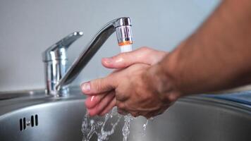 Close-up of faucet and hands, washing hands under trickle water. Emphasizing the importance of washing hands, this shows the proper technique of washing hands to ensure cleanliness and hygiene. video