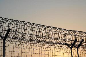 Barbed wire fence at sunset, close-up, security concept photo