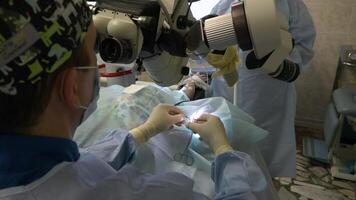 A group of surgeons in special clothes perform a microscopic operation on the patient's ENT organs using a surgical microscope. Innovative technologies in medicine video