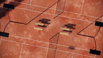 aerial view in vertical shot of Outdoor tennis court with red clay surface include net, lights, fence and spectator seats video