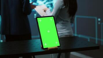Green screen tablet used by computer scientists in startup doing advancements in AI field. Employees working on mockup device in workspace featuring artificial intelligence systems, camera A video