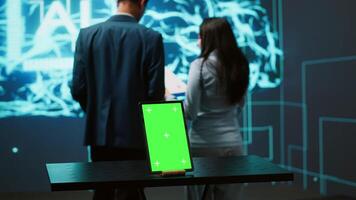 Engineers use green screen tablet and AI neural networks modeled after human brain to solve complex problems. Workers using artificial intelligence and mockup device to look at company data, camera A video