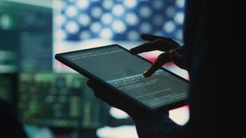 Cybersecurity expert in a governmental IT environment with the American flag. Monitoring cybersecurity, encryption and data security on a tablet to protect against cyber threats. Close up. Camera A. video