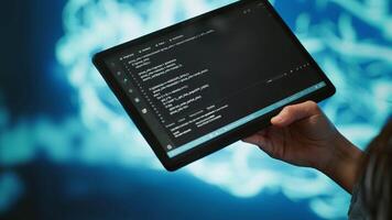 Software developer with tablet programming artificial intelligence computing simulating human brain. Close up of IT professional using device, building AI machine learning algorithms, camera A video