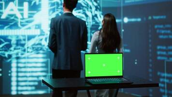 Teamworking AI technicians using green screen laptop for business data analysis. Team of IT experts works on mockup notebook to automatize tasks using artificial intelligence, camera A video