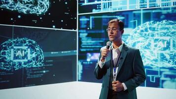 Presenter talking with spectators at AI convention bringing together IT specialists, sharing insights from latest developments in artificial intelligence and cognitive computing, camera B video
