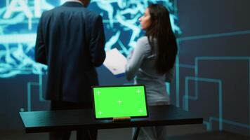 AI programmers colleagues using green screen laptop for business data analysis. IT experts in high tech location work on chroma key notebook to automatize tasks using artificial intelligence, camera A video