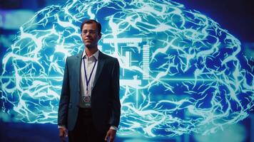 Smiling technician in startup stands with arms crossed, exuding professionalism and expertise. Portrait of cheerful Indian IT expert working in futuristic artificial intelligence workspace, camera B video