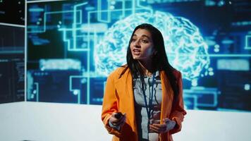 Presenter talking at AI neuroscience forum bringing together IT professionals, showing EEH headset demonstration of latest developments in artificial intelligence mind transfer, camera B video