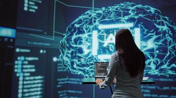 Computer scientist in startup doing advancements in AI field. Woman working on laptop in cutting edge workspace featuring artificial intelligence and neural network systems, camera B video