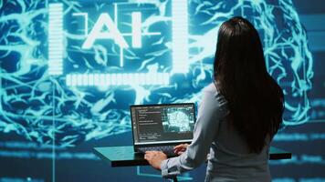Computer scientist in startup doing advancements in AI field. Woman working on laptop in cutting edge workspace featuring artificial intelligence and neural network systems, camera A video